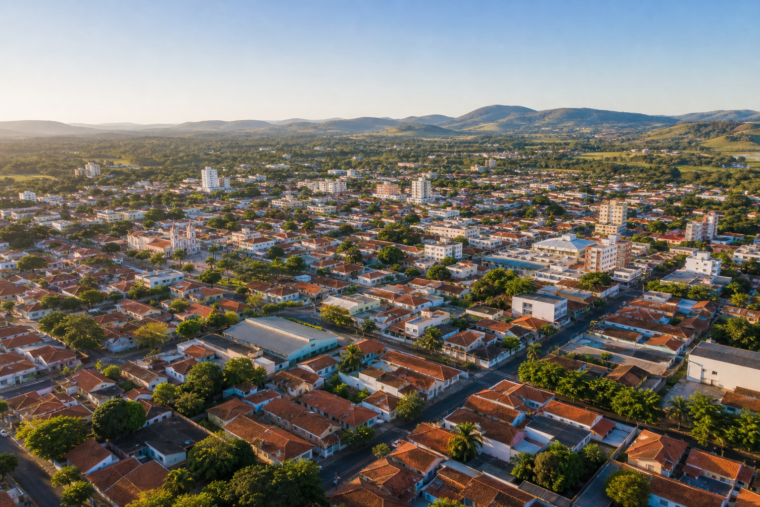 Vista aérea de cidade média brasileira com casas e áreas verdes sob luz natural